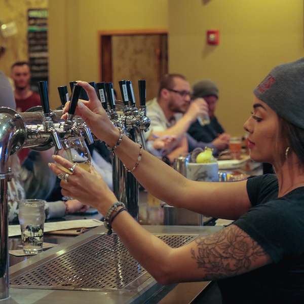 Female bartender pouring a beer.